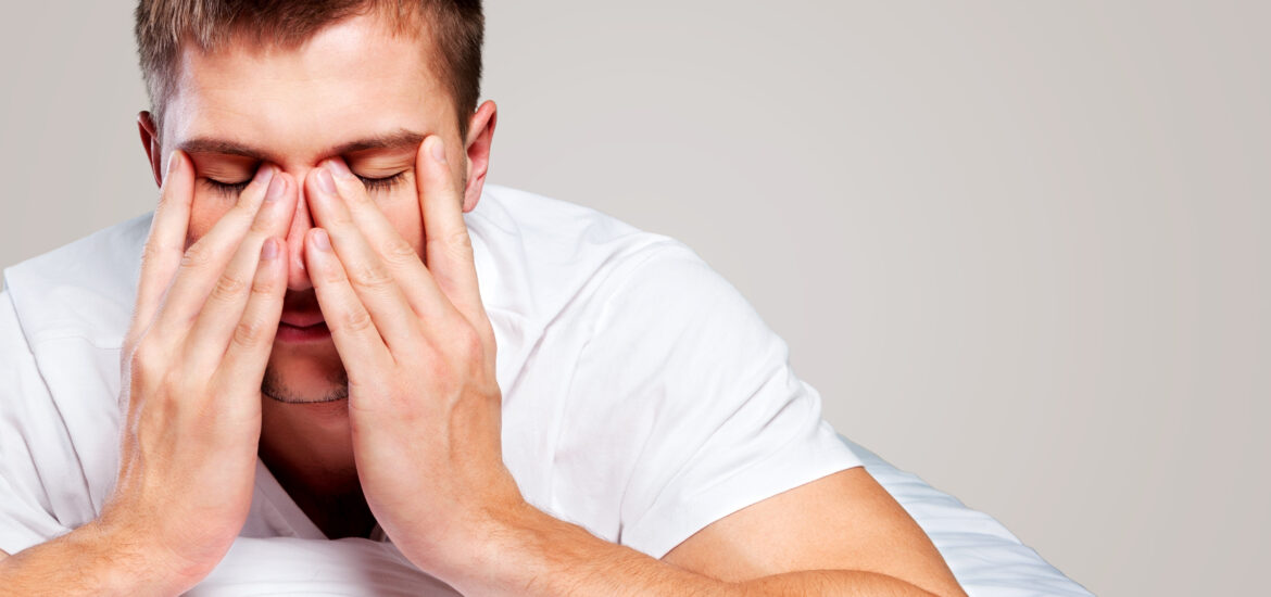 tired man with hands on face, sleep apnea sufferer