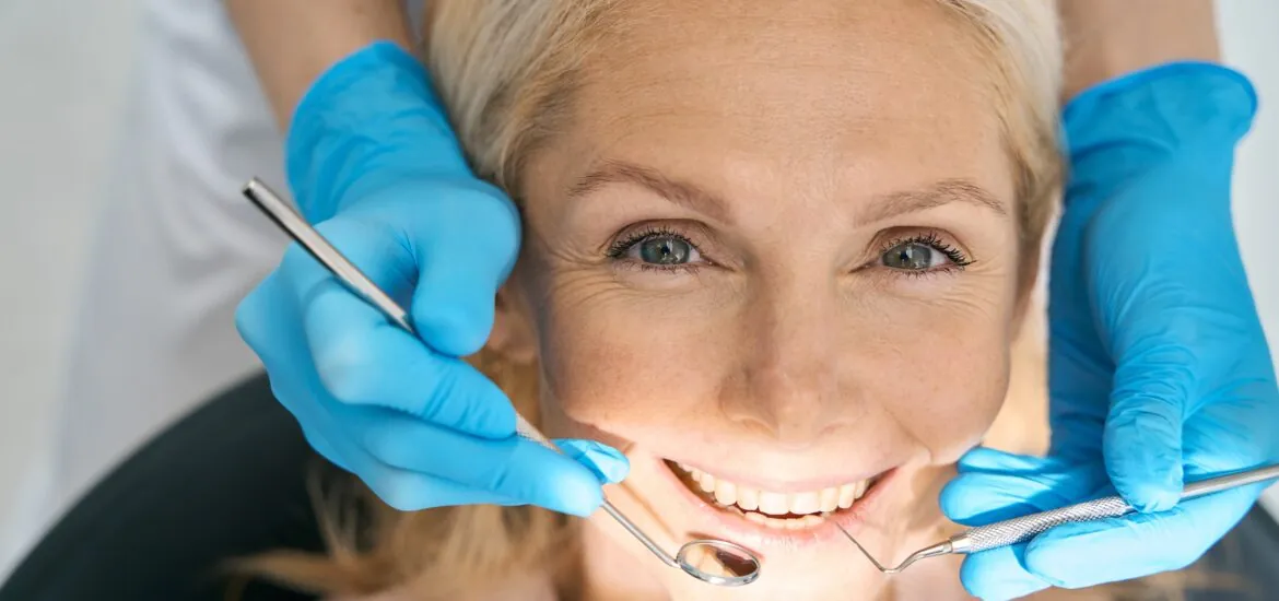 closeup of a woman having a doctor in blue gloves work on her dental bridge