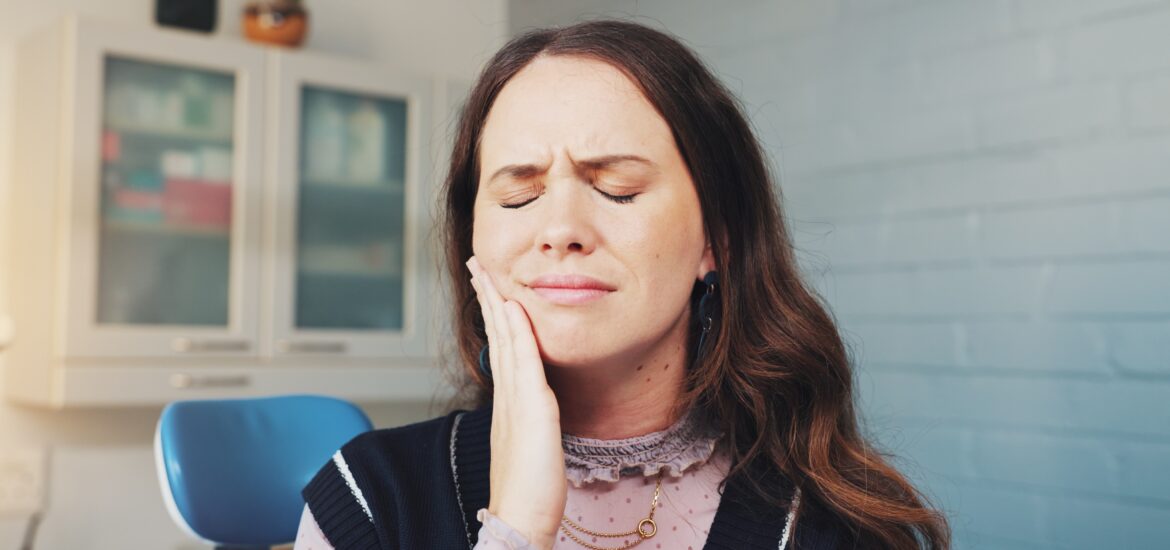 woman holding her jaw in pain, need for root canal